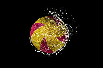 Image showing Volleyball ball flying in water drops and splashes isolated on black background