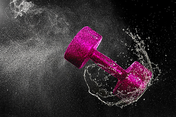 Image showing Dumbbell flying in water drops and splashes isolated on black background