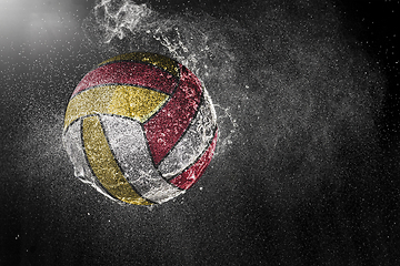 Image showing Volleyball ball flying in water drops and splashes isolated on black background