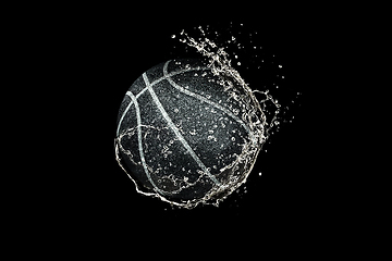 Image showing Basketball ball flying in water drops and splashes isolated on black background