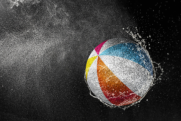 Image showing Volleyball ball flying in water drops and splashes isolated on black background