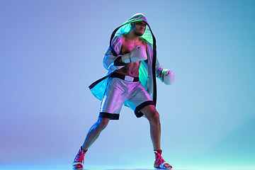 Image showing High-fashion styled man in white outfit pacticing box isolted over gradient background in neon light