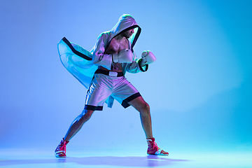 Image showing High-fashion styled man in white outfit pacticing box isolted over gradient background in neon light