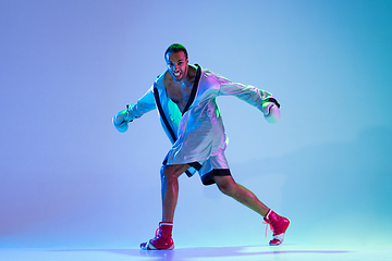 Image showing High-fashion styled man in white outfit pacticing box isolted over gradient background in neon light