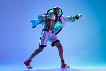 Image showing High-fashion styled man in white outfit pacticing box isolted over gradient background in neon light