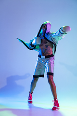 Image showing High-fashion styled man in white outfit pacticing box isolted over gradient background in neon light