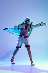 Image showing High-fashion styled man in white outfit pacticing box isolted over gradient background in neon light