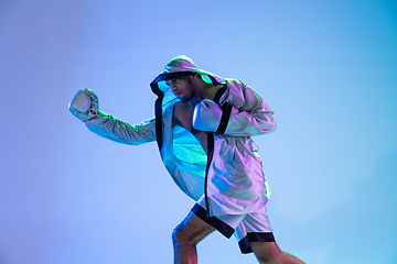 Image showing High-fashion styled man in white outfit pacticing box isolted over gradient background in neon light