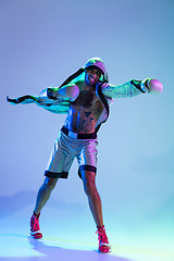 Image showing High-fashion styled man in white outfit pacticing box isolted over gradient background in neon light