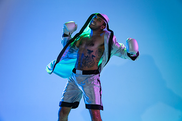 Image showing High-fashion styled man in white outfit pacticing box isolted over gradient background in neon light