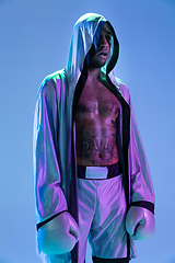 Image showing High-fashion styled man in white outfit pacticing box isolted over gradient background in neon light