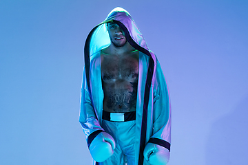 Image showing High-fashion styled man in white outfit pacticing box isolted over gradient background in neon light