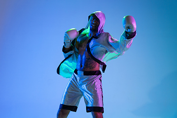 Image showing High-fashion styled man in white outfit pacticing box isolted over gradient background in neon light