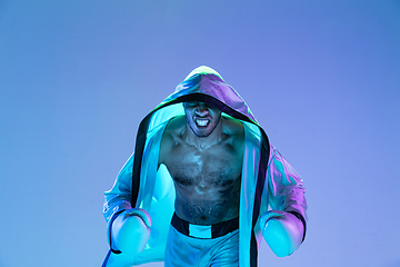 Image showing High-fashion styled man in white outfit pacticing box isolted over gradient background in neon light