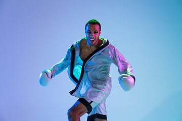 Image showing High-fashion styled man in white outfit pacticing box isolted over gradient background in neon light