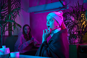 Image showing Beautiful girl with a pearl earring taking lunch in modern cafe, restaurant in neon light