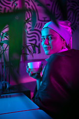 Image showing Beautiful girl with a pearl earring taking lunch in modern cafe, restaurant in neon light