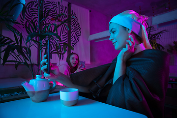 Image showing Beautiful girl with a pearl earring taking lunch in modern cafe, restaurant in neon light