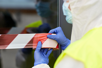 Image showing healthcare worker sealing door with caution tape