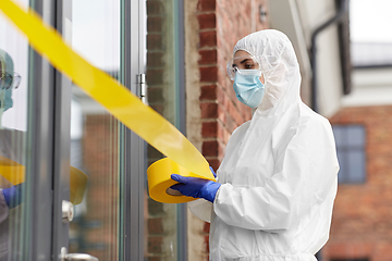 Image showing healthcare worker sealing door with caution tape