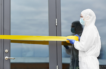 Image showing healthcare worker sealing door with caution tape