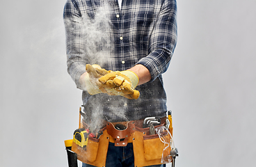 Image showing builder with working tools and gloves using talc