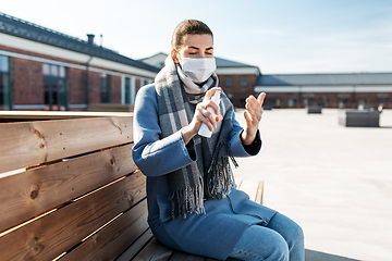 Image showing woman in mask spraying hand sanitizer outdoors