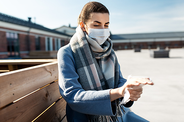 Image showing woman in mask cleaning hands with wet wipe in city