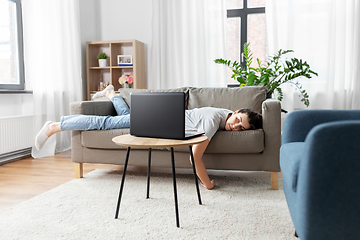 Image showing bored woman with laptop lying on sofa at home