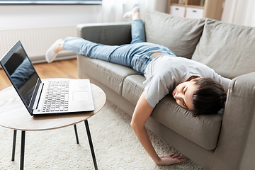 Image showing bored woman with laptop lying on sofa at home