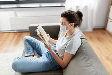 Image showing sick woman in medical mask reading book at home