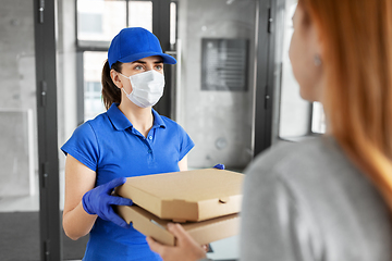 Image showing delivery girl in mask giving pizza boxes to woman