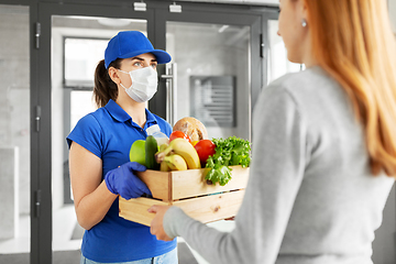 Image showing delivery girl in mask giving box of food to woman