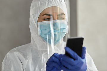 Image showing doctor in protective wear with smartphone