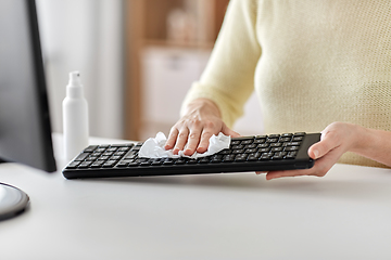 Image showing close up of woman cleaning keyboard with tissue