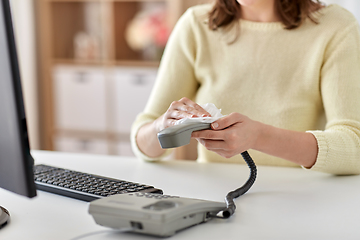 Image showing close up of woman cleaning desk phone with tissue