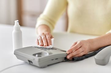 Image showing close up of woman cleaning desk phone with tissue