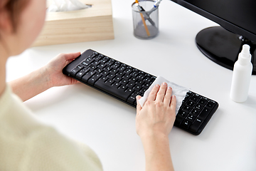 Image showing close up of woman cleaning keyboard with tissue