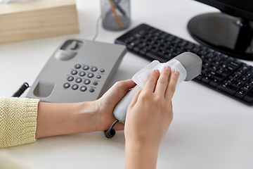 Image showing close up of woman cleaning desk phone with tissue