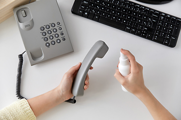 Image showing close up of woman cleaning phone with sanitizer