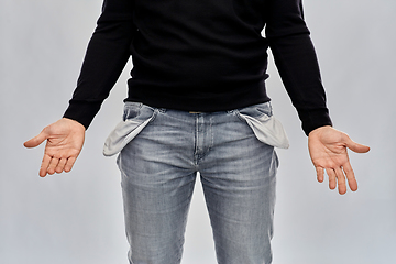 Image showing close up of man showing empty pockets over grey