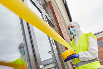 Image showing healthcare worker sealing door with caution tape