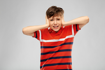 Image showing boy closing ears with hands over grey background