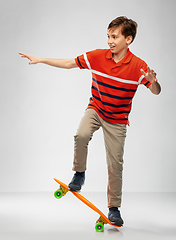 Image showing smiling boy riding on short skateboard