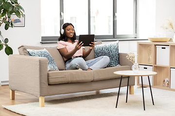 Image showing woman with tablet pc listening to music at home