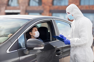 Image showing healthcare worker with clipboard and woman in car