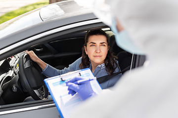 Image showing healthcare worker with clipboard and woman in car