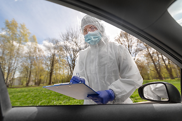 Image showing doctor in hazmat suit with clipboard at car