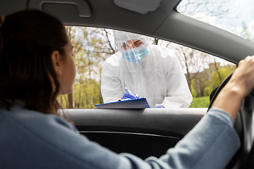 Image showing healthcare worker with clipboard and woman in car