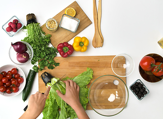 Image showing hands cutting lettuce on wooden board at kitchen